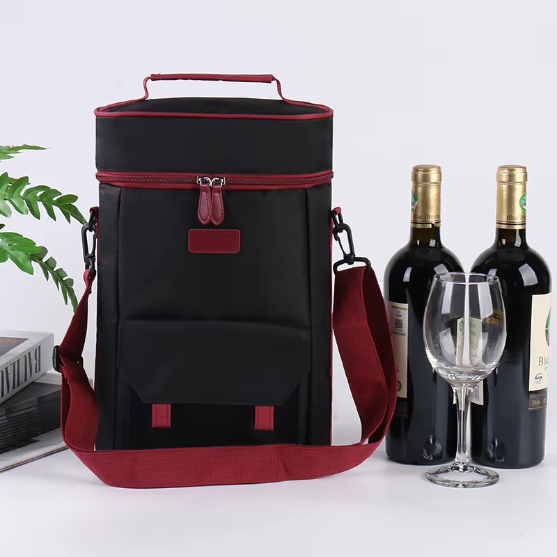 black bag with red piping beside two wine bottles and glass