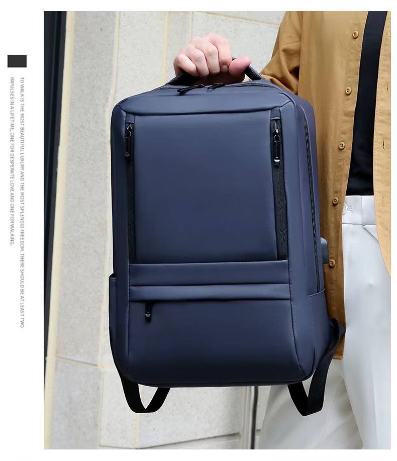 man holding navy blue backpack by top handle