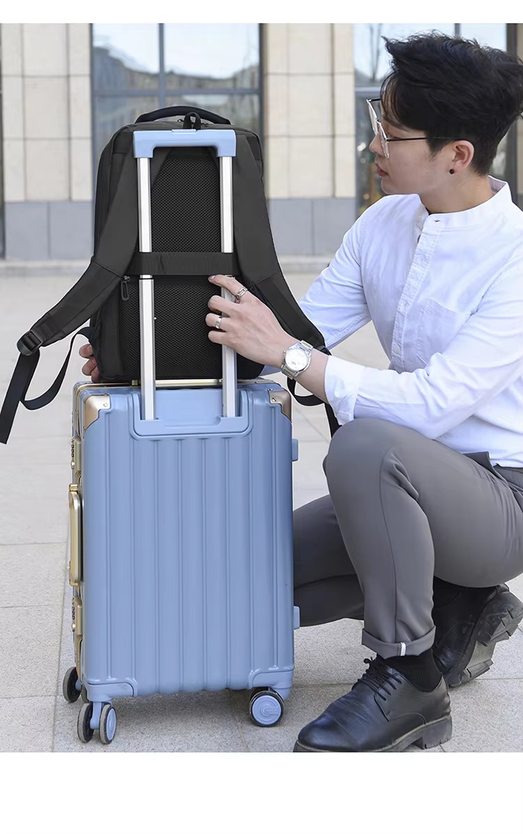 backpack mounted on rolling luggage handle while man kneels beside it