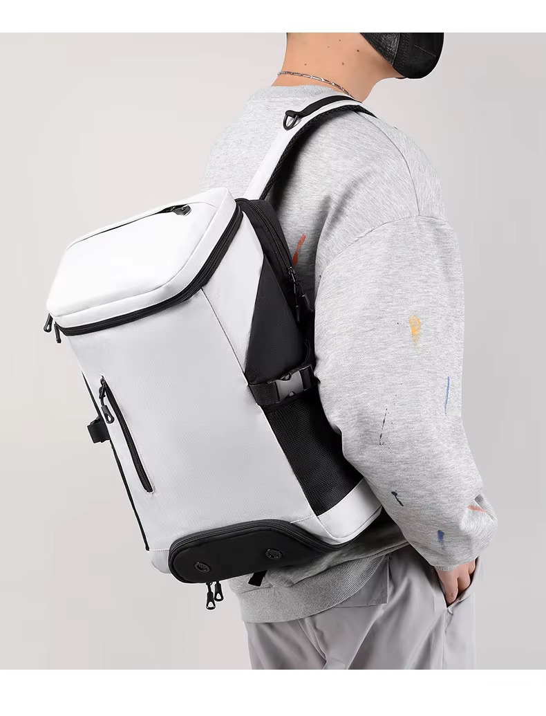 model holding teal backpack out in front of him by the handle