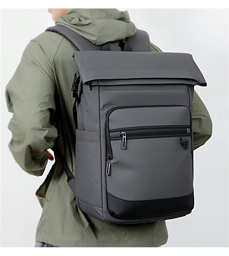 man wearing grey rolltop backpack from behind