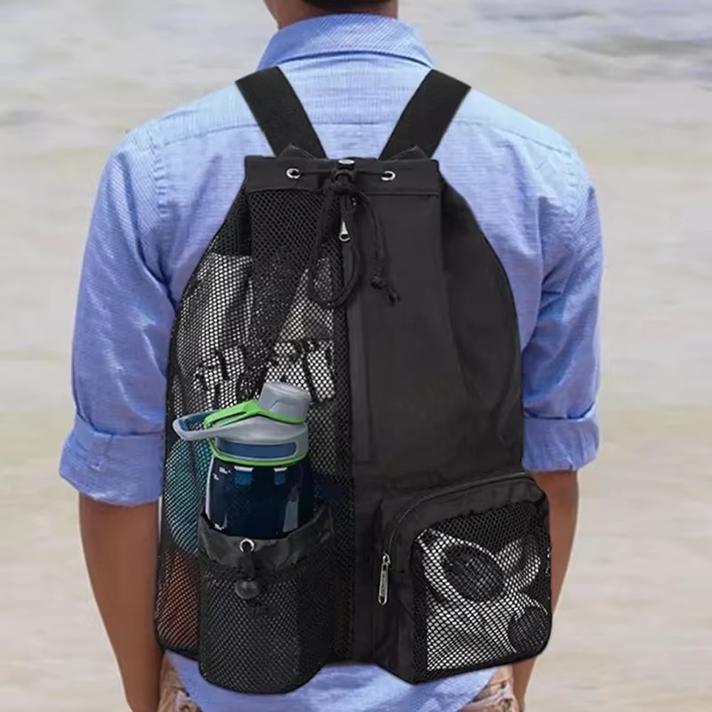man wearing black mesh backpack from behind at the beach