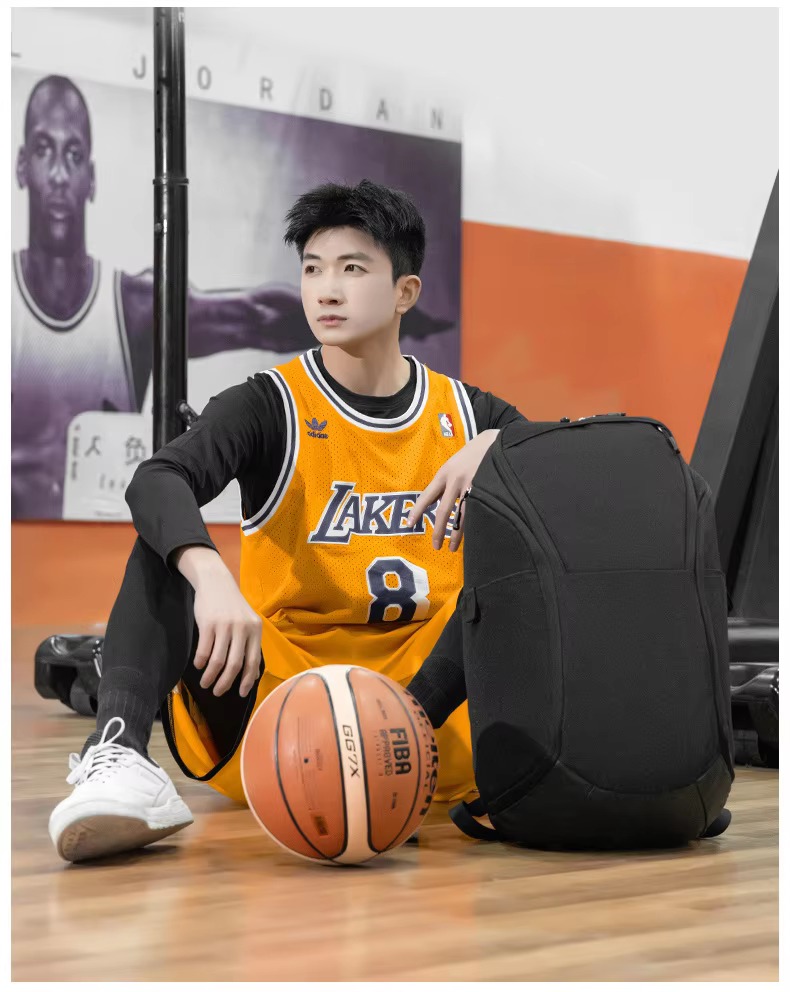 man seated beside black backpack on court