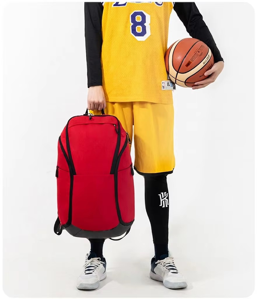 man holding red backpack by top handle
