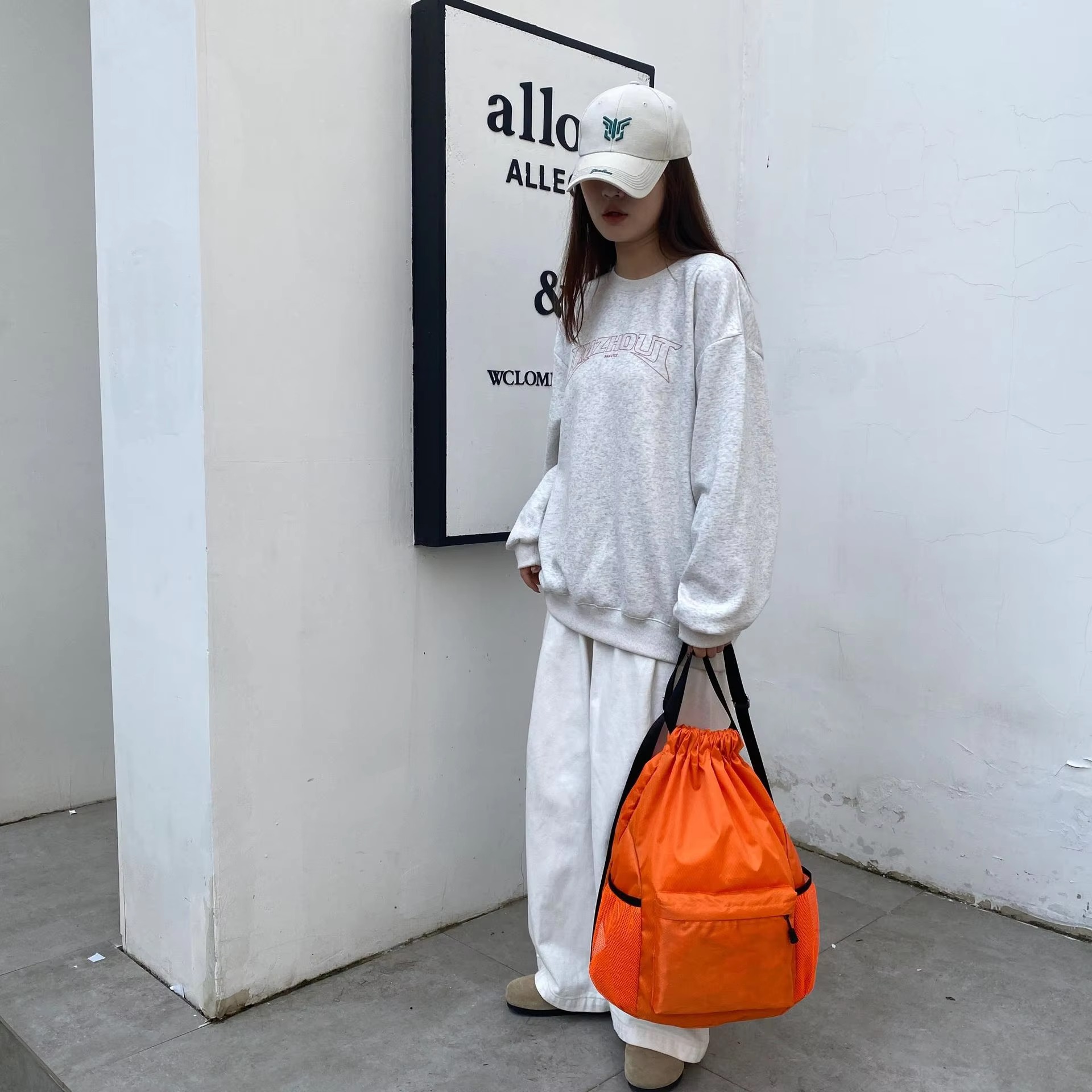 woman carrying orange backpack by hand