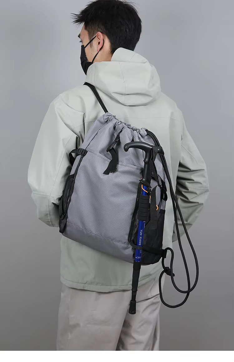 man wearing gray backpack with trekking pole