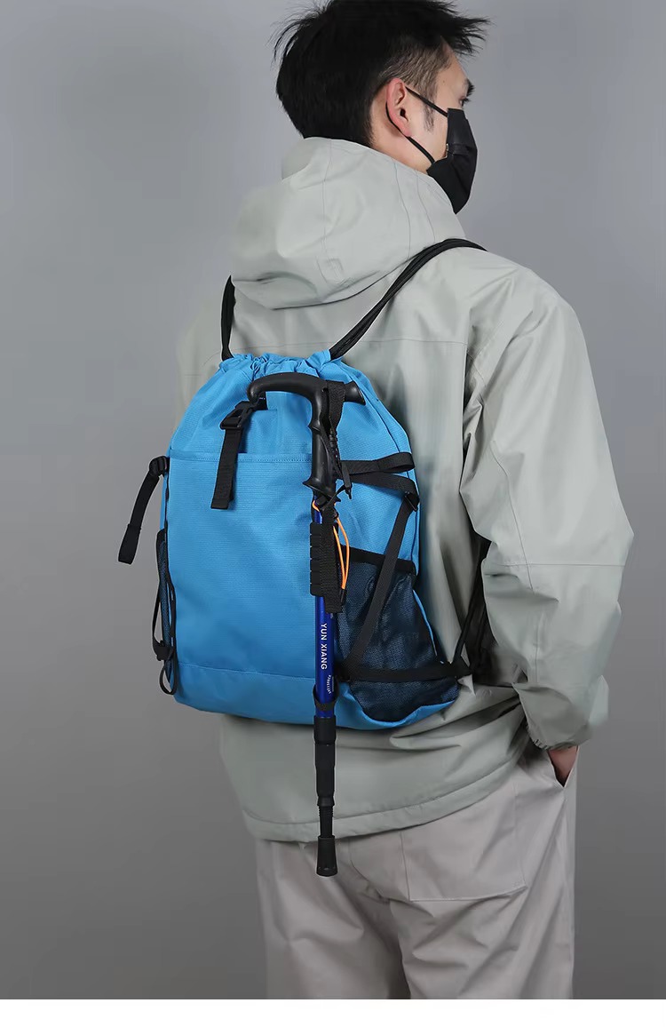 man wearing sky blue backpack with trekking pole
