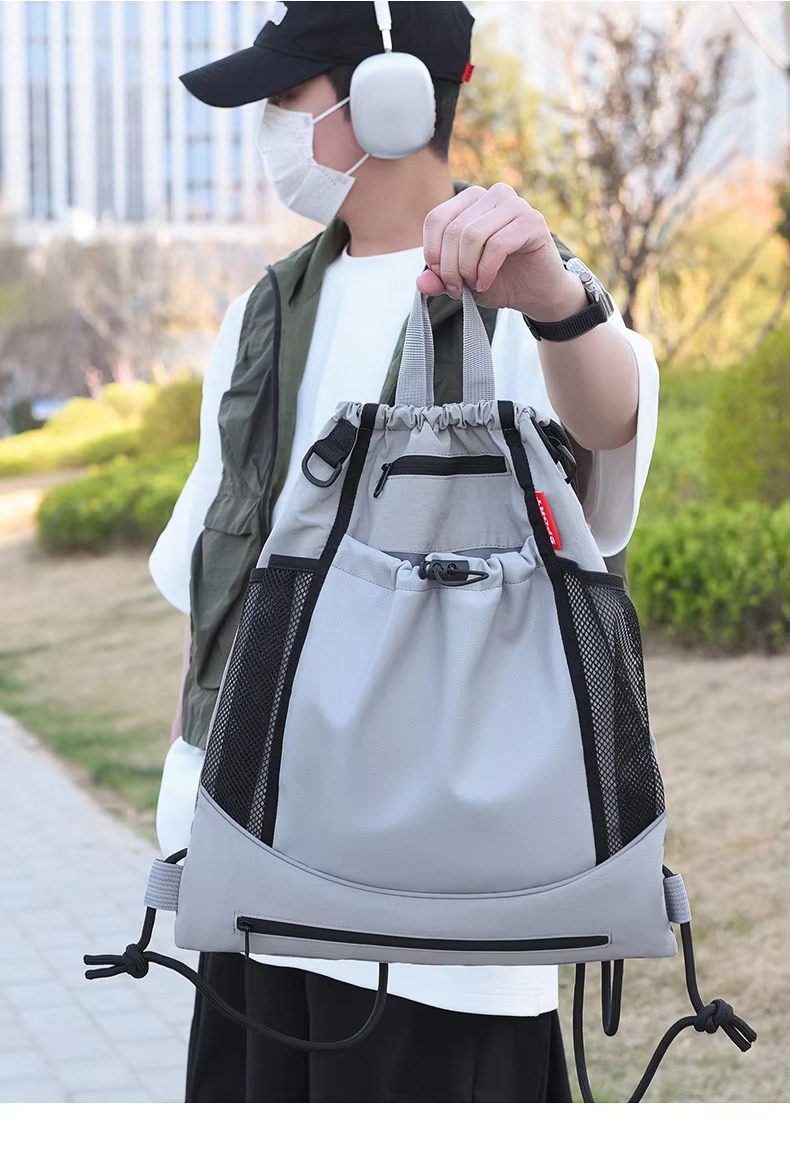 man holding grey backpack