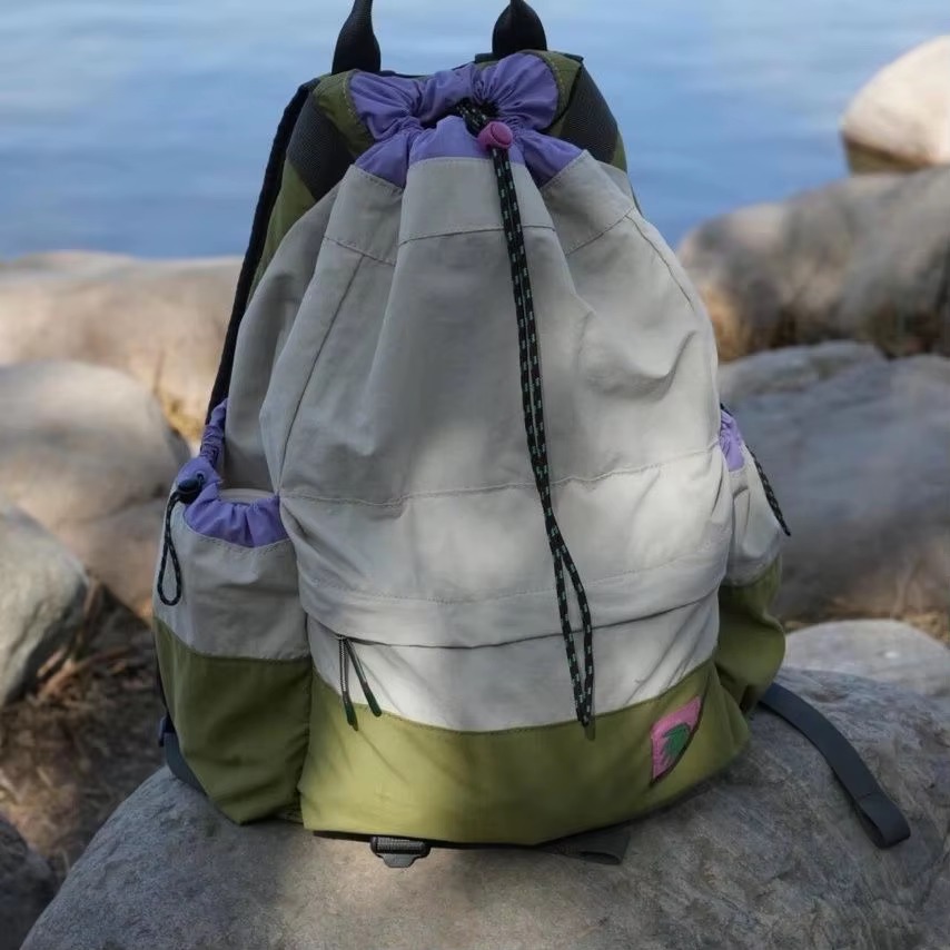 color-block drawstring backpack on rock by lake