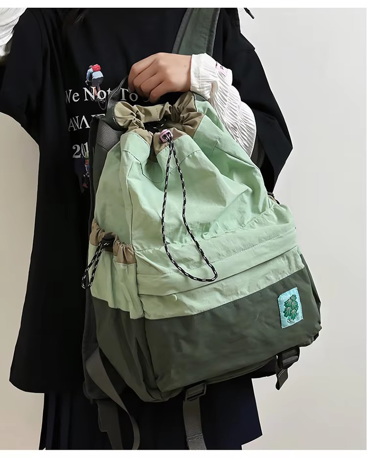 student holding green backpack by handle