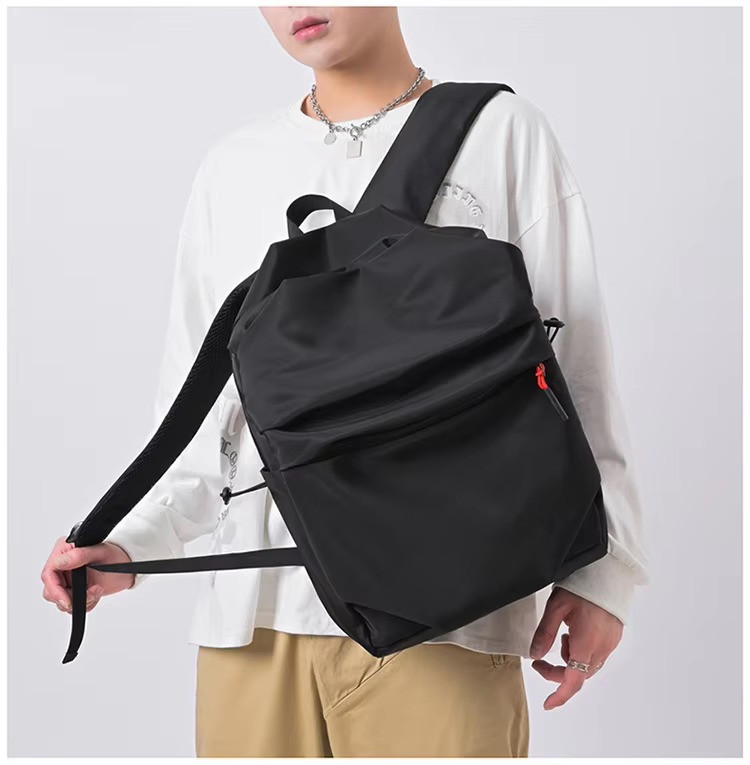 man holding black backpack straps