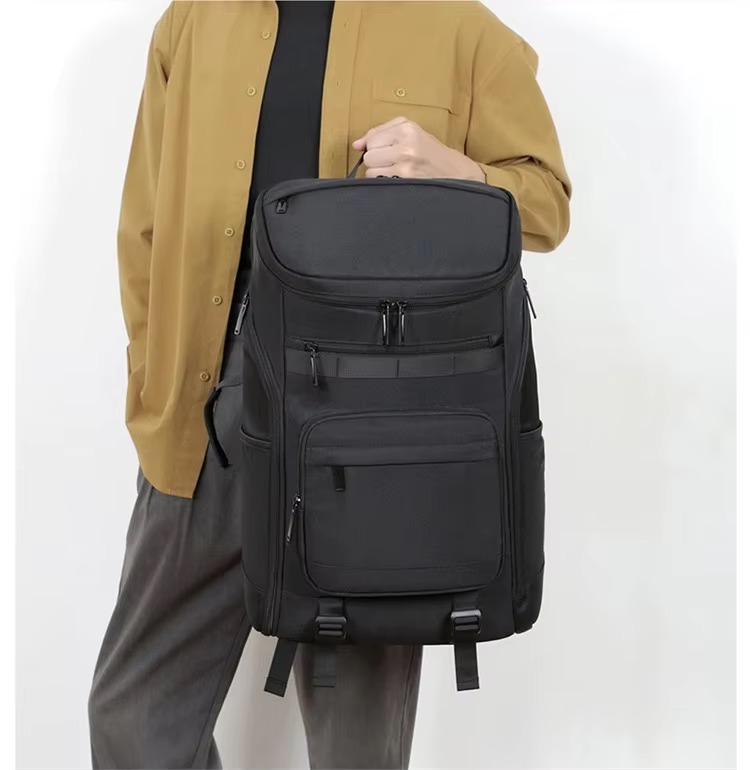 man holding black backpack by top handle