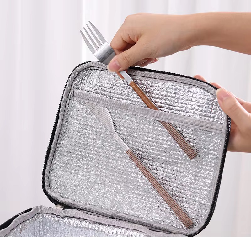 top compartment open with foil lining and mesh divider holding a fork and chopsticks