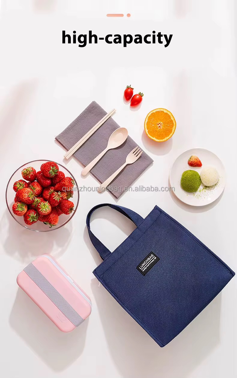 navy bag on table beside fruit tableware and pink lunch box high capacity caption