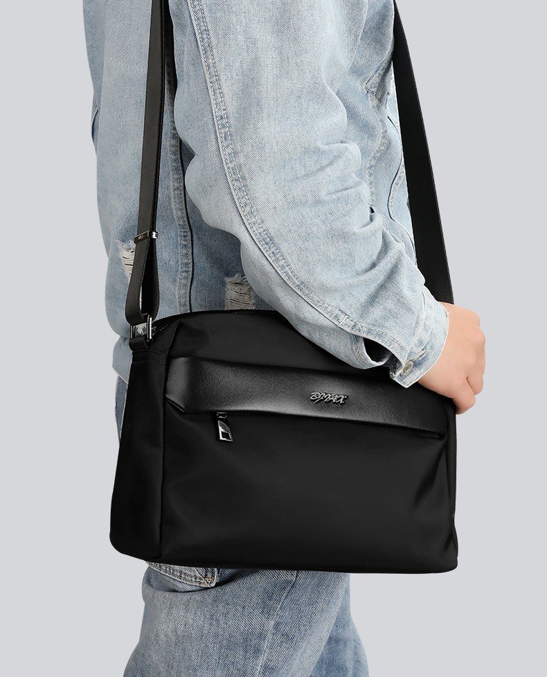 man wearing black bag crossbody close view against denim jacket