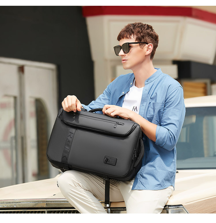 model carrying the backpack by its side handle