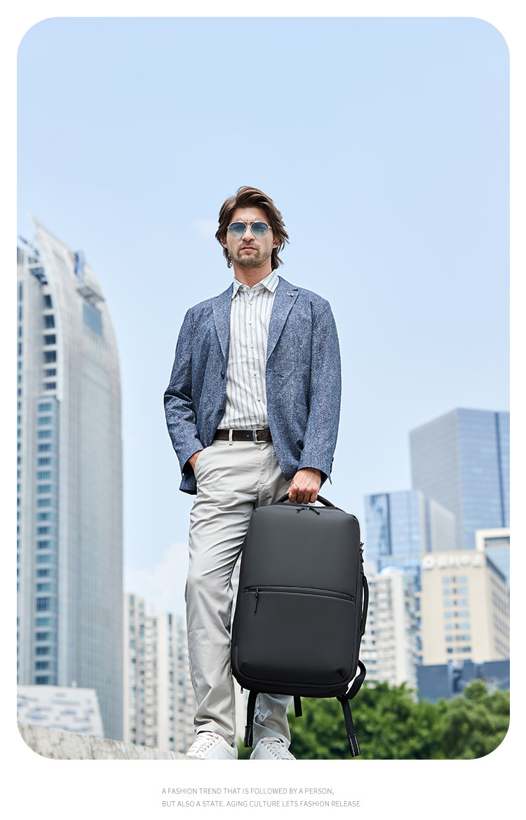 model standing holding the backpack at his side, city skyline background
